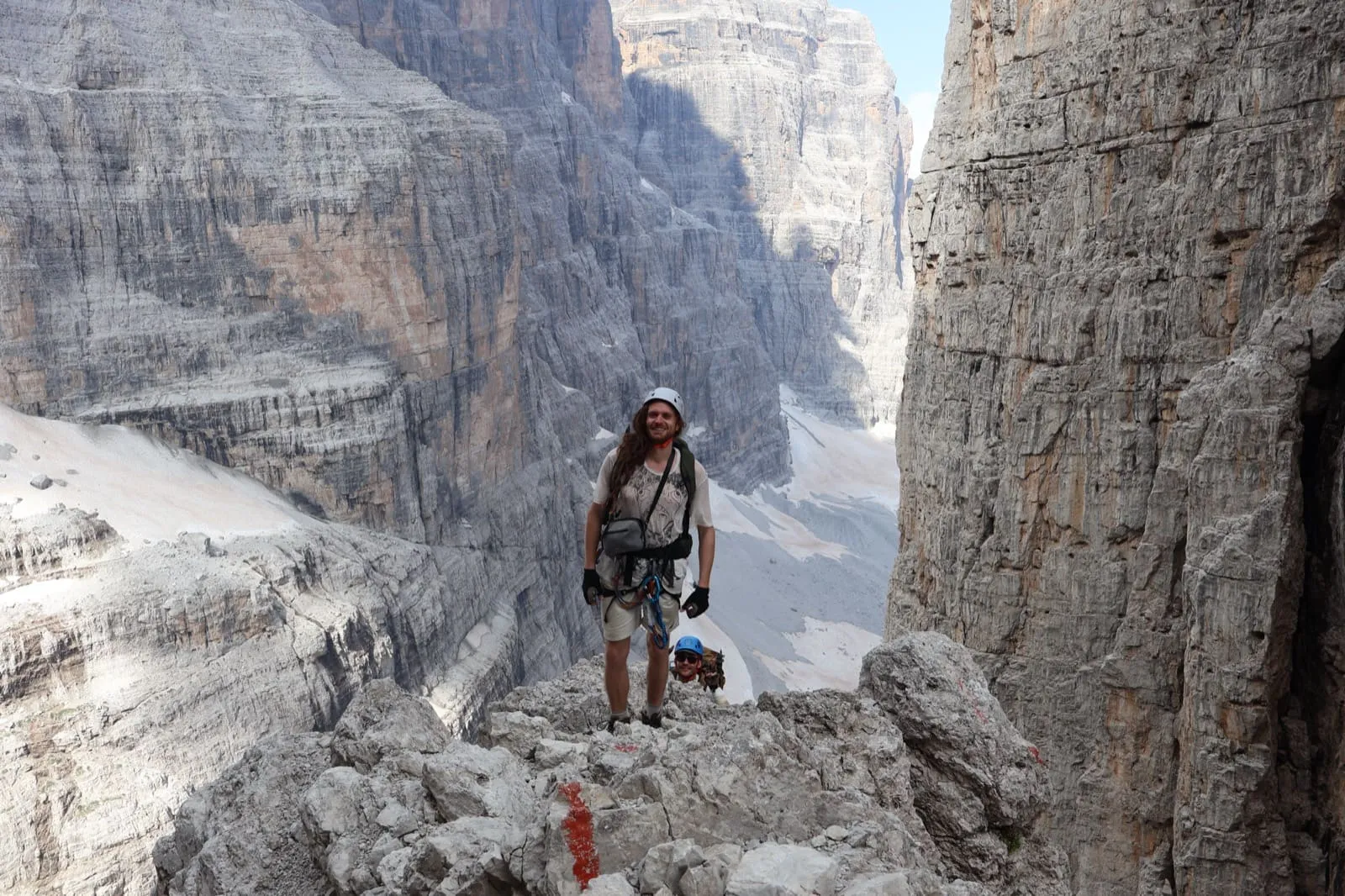 Standing in a narrow limestone gully in the Dolomites, climbing helmet on